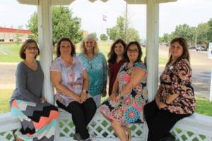 A group of women sitting on top of a white gazebo.