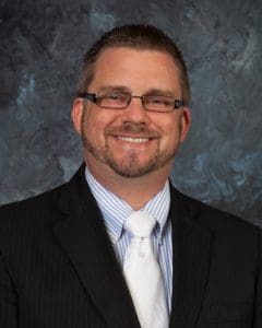 A man in a suit and tie smiling for the camera.