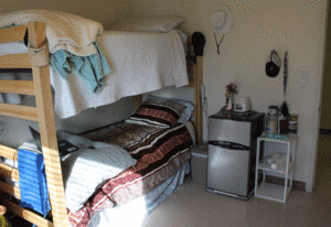 A small bedroom with a bed and refrigerator.