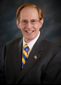 A man in a suit and tie smiling for the camera.