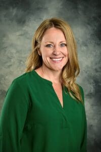 A woman in green shirt smiling for the camera.