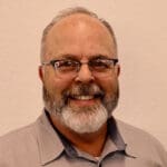 A man with glasses and beard smiling for the camera.