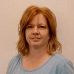 A woman with red hair and blue shirt.