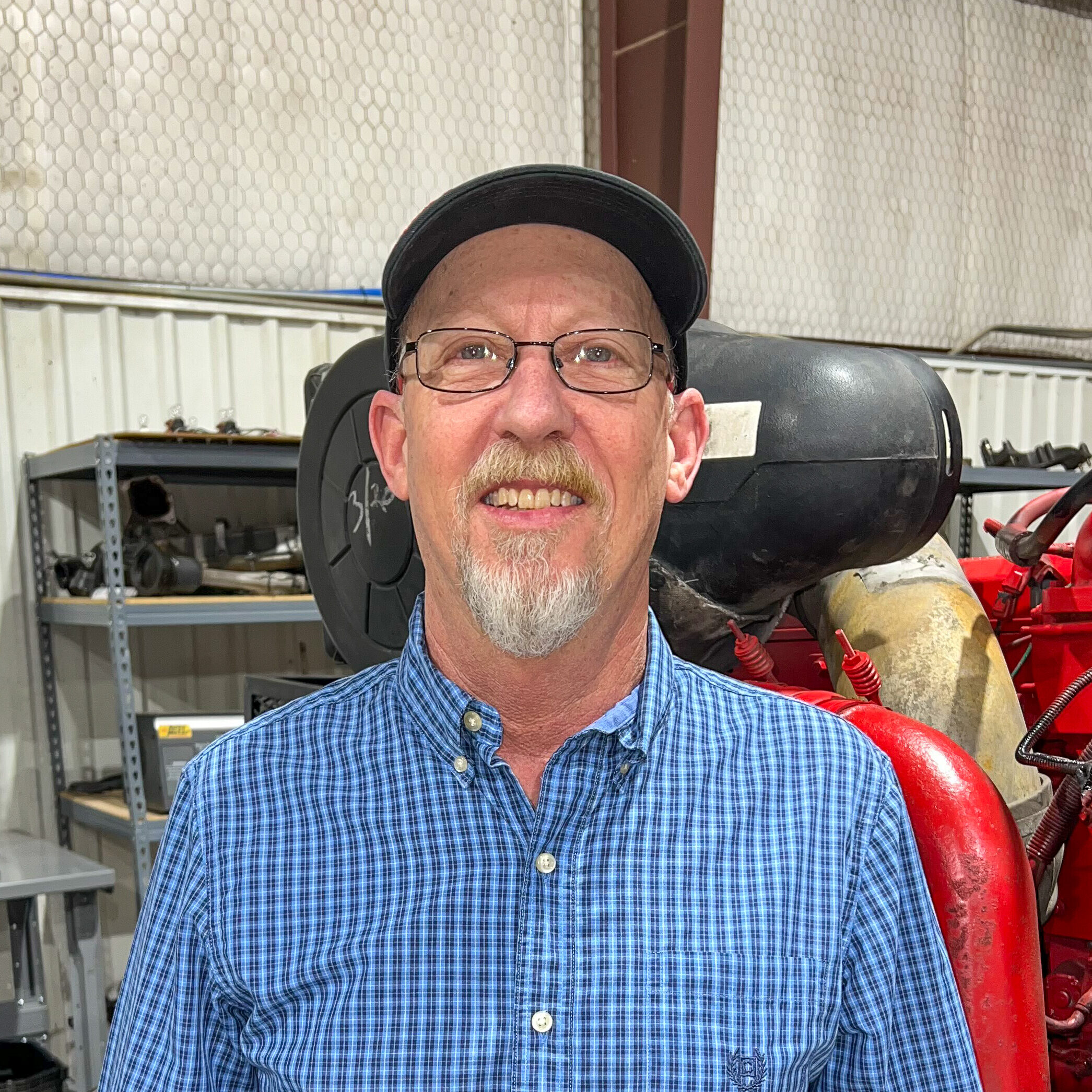 A man in glasses and a hat standing next to fire hydrants.