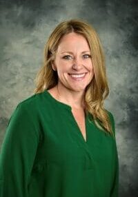 A woman in green shirt smiling for the camera.